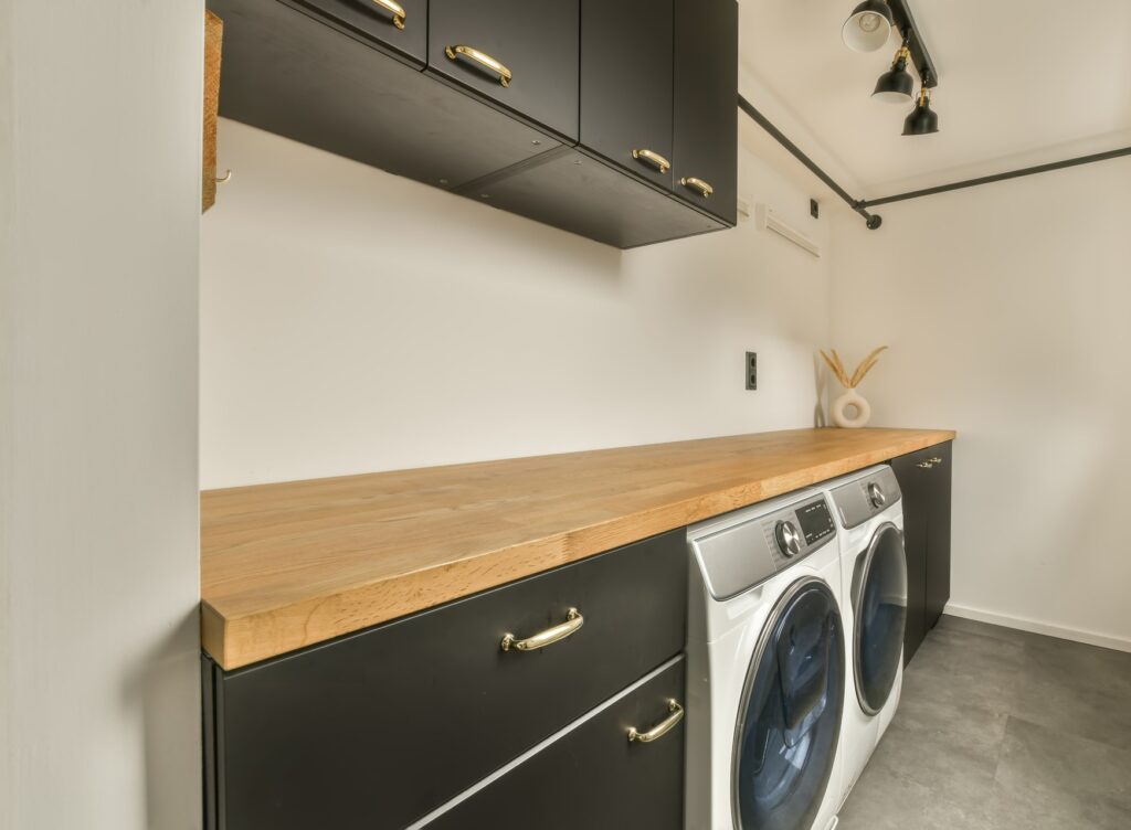 Spacious laundry room with appropriate equipment and lots of black cabinets in a modern house