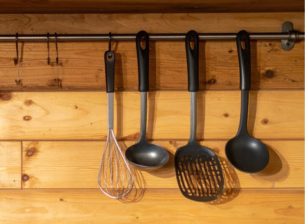 Kitchen with wooden walls and shelf with uts and uts hanging from.