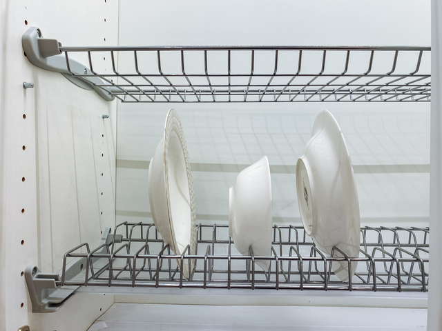 A dish rack that is holding various plates and bowls neatly arranged on it, showcasing an organized kitchen space, contributing to a functional and aesthetic home environment