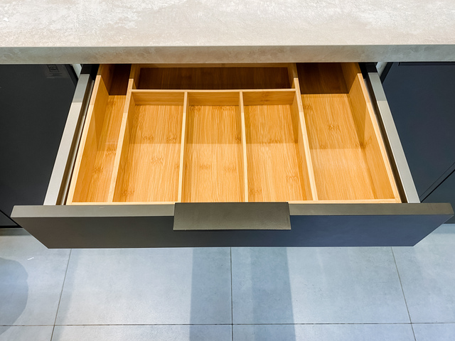 A kitchen drawer with a wooden cutlery tray in it