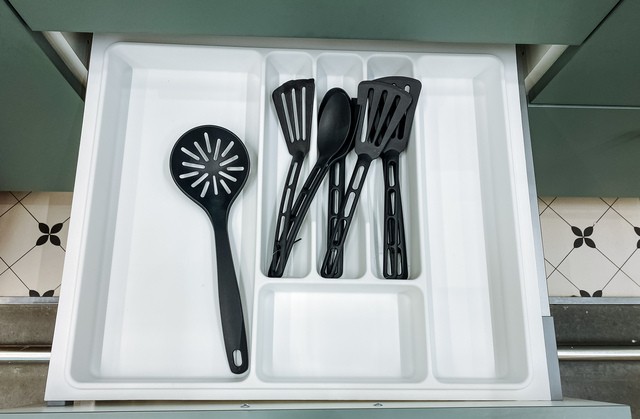drawer contains various kitchen utensils, revealing the assortment of items used for cooking and food preparation, such as cutlery and other tools