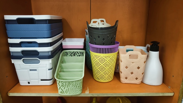 Collection of various plastic storage bins and baskets on a shelf for home organization