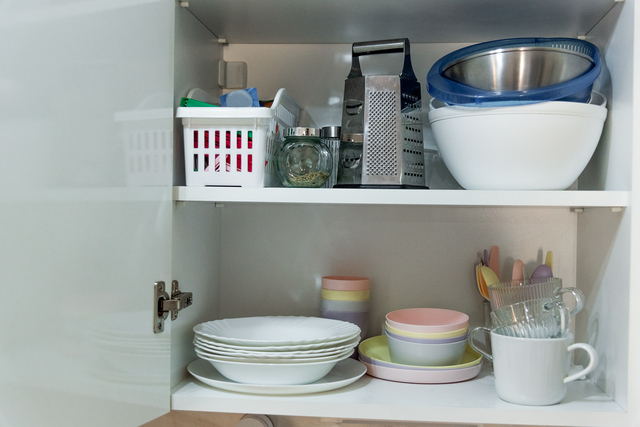 Dishes, plates and mugs on shelf cabinet, organization space in kitchen interior