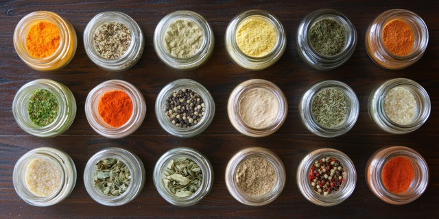 Diverse collection of colorful spices in glass jars on dark wooden background