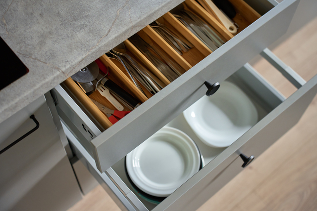 Modern kitchen cabinets with dishes and cutlery in open drawers
