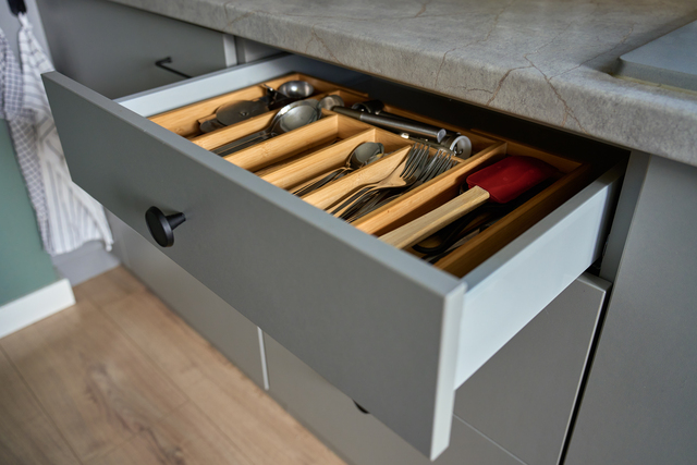 Open kitchen drawer with arranged set of cutlery and cooking utensils