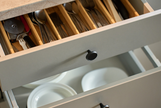 Modern kitchen cabinets with dishes and cutlery in open drawers