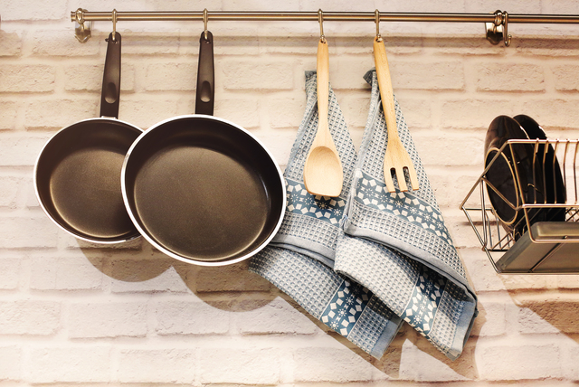 Utensils and pans hanging on railing above counter