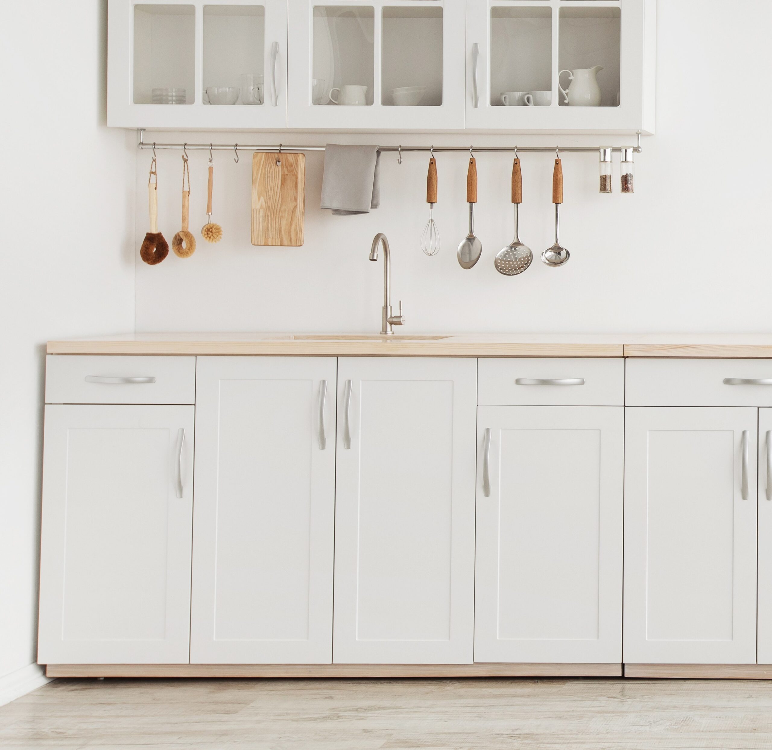 Minimal light scandinavian kitchen interior. White furniture with utensils, shelves with crockery, small refrigerator